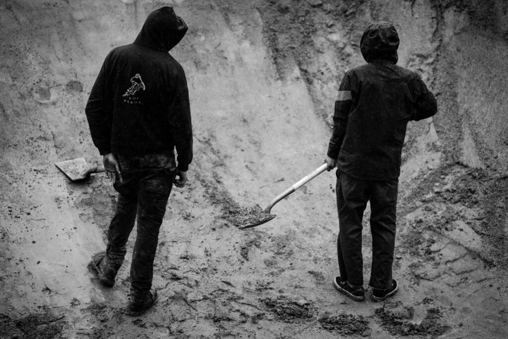 Two men standing with shovels on mountain bike trail