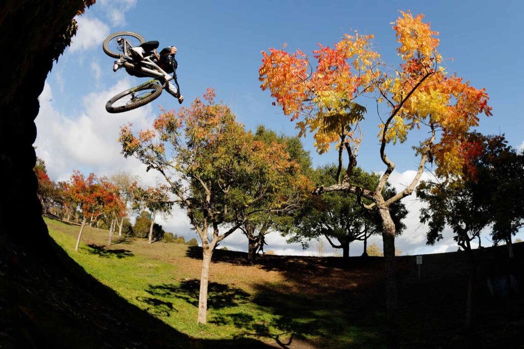 Mountain biker mid air with fall foliage in background